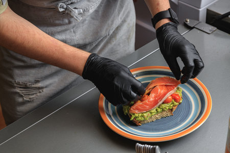Close up of chef hands cooking avocado toast with salmon for breakfast menu in restaurant kitchenの写真素材