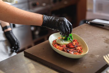 Professional chef is decorating ready meal with greens on restaurant kitchenの写真素材