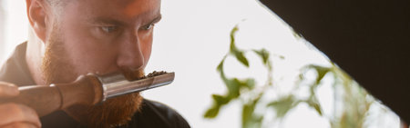Close up of barista inhaling the aroma of coffee beans in own manufacturingの写真素材