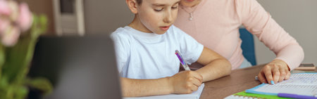 Portrait of beautiful mother helping small teen son with homework in copybook.