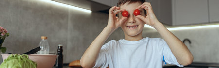 Portrait of small teen Caucasian boy cooking in kitchen and playing with vegetables.の写真素材