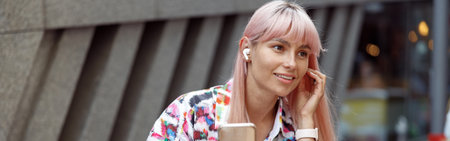 Female inserting second earbud into ear outdoorsの写真素材