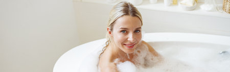 Portrait of young beautiful young Caucasian woman smiling while enjoying hot bath with foam.