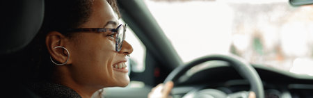 Smiling businesswoman driving car and holding both hands on steering wheel on the way to workの写真素材