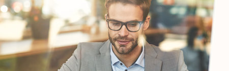 Front view of a young busy caucasian businessman or male freelancer using laptop while working remotely in cafeの写真素材