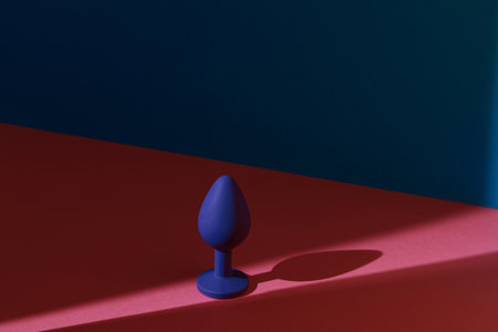 Blue buttplug sex toy on a colorful background. Photo of anal toy for adult with contrast shadowsの写真素材
