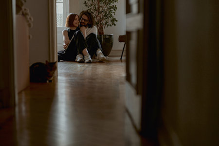 Smiling couple hugging and enjoying time together while sitting floor at home with cat on backgroundの写真素材