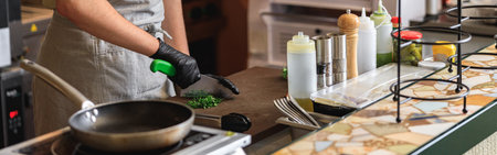 Male chef hands using professional knife to chop finely fresh organic herbs for recipe