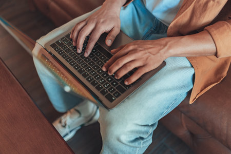 Close up of man freelancer working on laptop while sitting on sofa in cozy coworkingの写真素材