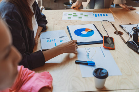 Close up of business team analyzing income charts and graphs during meeting in officeの写真素材