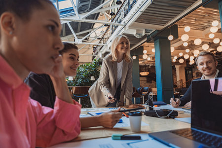 Group of smiling colleagues is discussing project during meeting in modern coworking