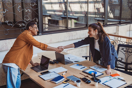 Two smiling professional business people shaking hands at office meeting. Partnership conceptの写真素材