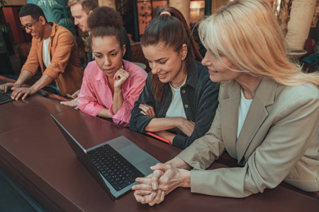 Friendly diverse business people laughing working on project together in modern coworking