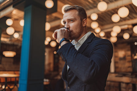Portrait of handsome businessman is drinking coffee during working day in modern coworkingの写真素材