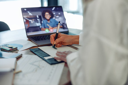 Close up of woman freelancer have video conference with client and making notes sitting near windowの写真素材