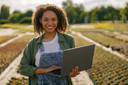 Woman gardener working on laptop while sitting on background of shop plants centerの写真素材