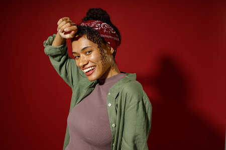 Happy woman looks camera with smile while posing on red studio background
