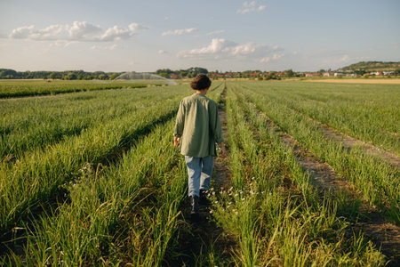 Back view of female farmer walks across an field during harvesting. Agricultural occupation concept