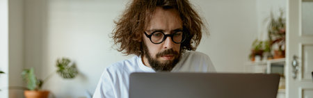 Thoughtful man freelancer sitting at desk and working at laptop in home office. Remote workの写真素材