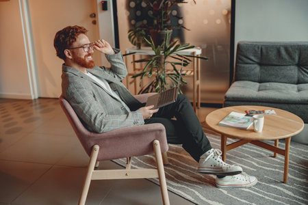 Handsome entrepreneur working on laptop sitting in modern coworking during working dayの写真素材