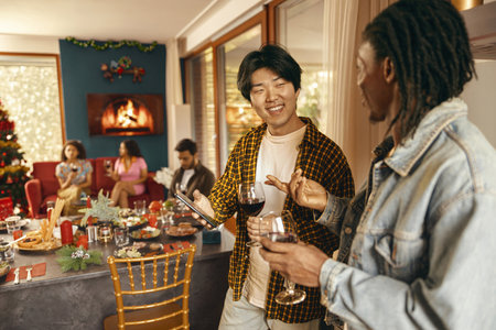 Happy friends enjoying in conversation and drinking wine during festive dinner at home partyの写真素材
