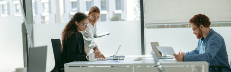 Female boss shows something in notebook to employee during working day in officeの写真素材