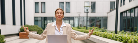 Woman freelancer working on laptop while sitting outside in lotus position on office backgroundの写真素材