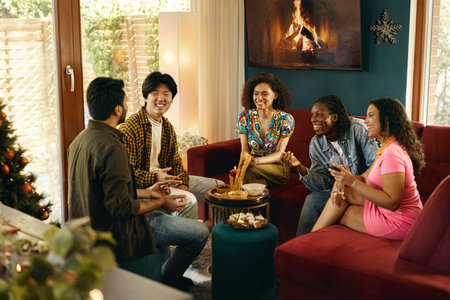 Group of smiling friends enjoying in conversation and drinking wine during Christmas party at homeの写真素材
