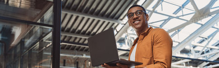 Smiling businessman in casual clothing working on laptop while standing on coworking backgroundの写真素材