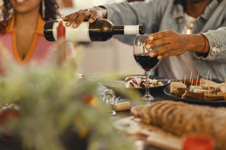 Close up of man pouring red wine into glass during festive dinner partyの写真素材