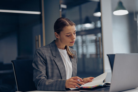 Stylish female freelancer working with documents and laptop while sitting in modern coworkingの写真素材