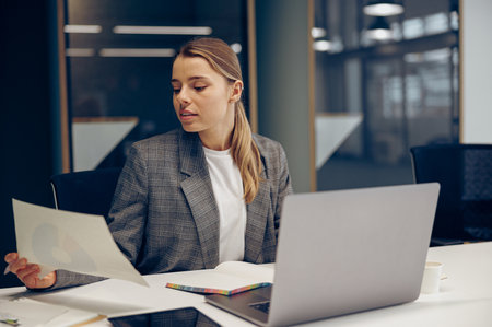 Focused business woman working with documents and use laptop while sitting the desk in officeの写真素材