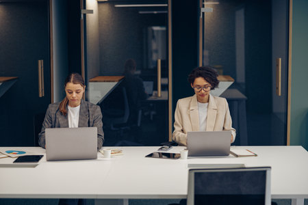 Concentrated female office workers working on project and use laptops sitting in coworkingの写真素材