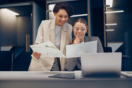 Two female professional executives experts discussing financial accounting papers working togetherの写真素材