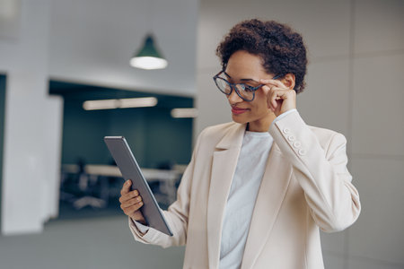 Smiling female freelancer is working on digital tablet standing on coworking backgroundの写真素材