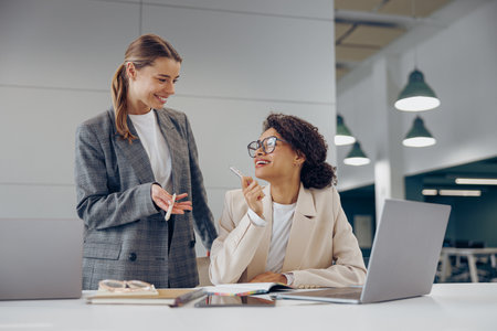 Smiling business woman work together to get the job done at the office and use laptopの写真素材