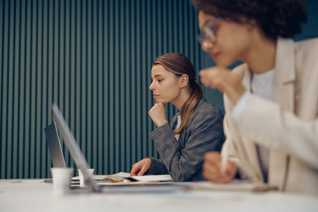Serious female office workers working on project and use laptops sitting in coworkingの写真素材