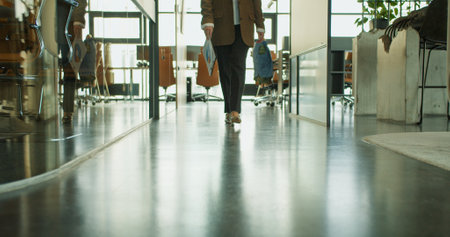 A businesswoman walking confidently in a modern office hallway, showcasing corporate elegance and...