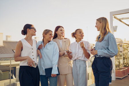 A group of women engaged in an enjoyable conversation on a wonderful rooftop settingの写真素材