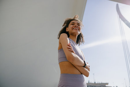 Woman in sportswear have a rest after workout standing with crossed hands on building backgroundの写真素材