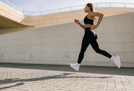 Active woman athlete is jogging on morning on modern building background. Healthy life conceptの写真素材