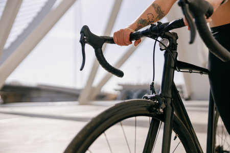 Close up of woman cyclist standing with her bike while training outdoorsの写真素材