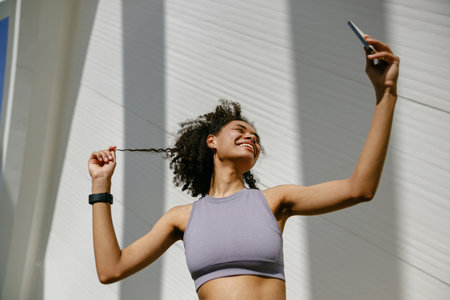 Portrait of sporty smiling young woman after running making selfie outdoorsの写真素材