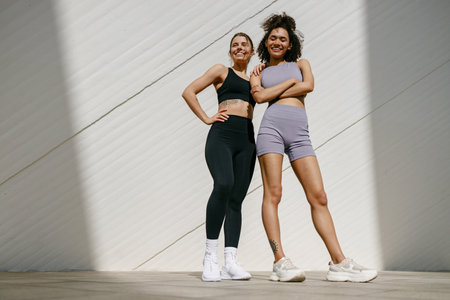 Smiling female sportswomen have a rest after morning jogging standing outdoorsの写真素材