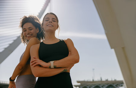 Two young female sportswomen have a rest after morning jogging standing outdoors and looks cameraの写真素材