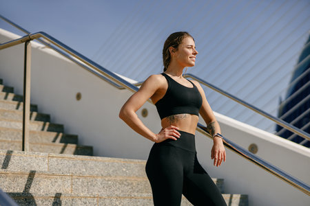 Female athlete in sportswear have a rest after morning jogging outside and looks awayの写真素材
