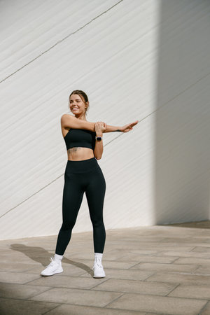 Smiling woman in tracksuit stretching outdoor and preparing to jogging. Healthy life conceptの写真素材