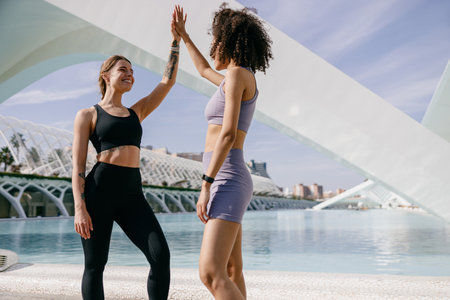 Happy female friends doing gesture of sport shake hand after exercising outsideの写真素材