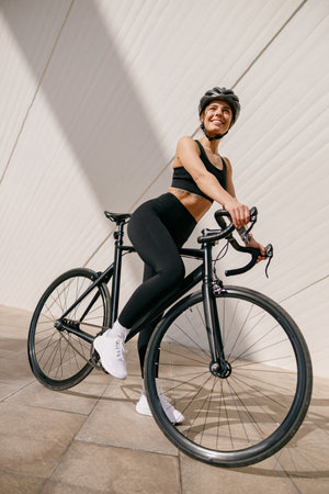 Active female cyclist in sportswear helmet cycle outdoors on city building backgroundの写真素材