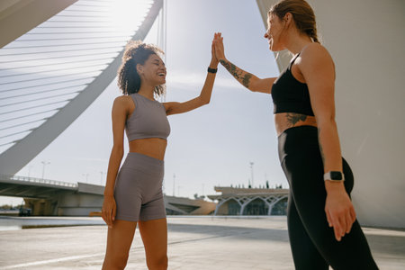 Happy female friends doing gesture of sport shake hand after exercising outside